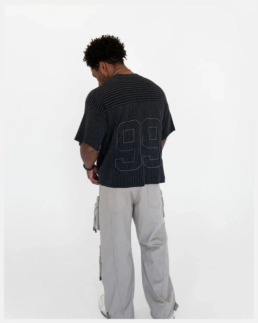 Man wearing a black striped shirt with number 99 on back and light cargo pants, rear view