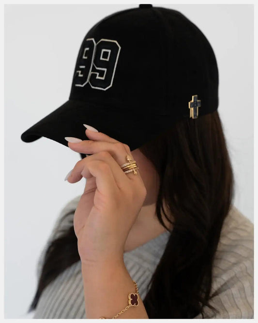 Black suede baseball cap with white number 99 and gold cross emblem.